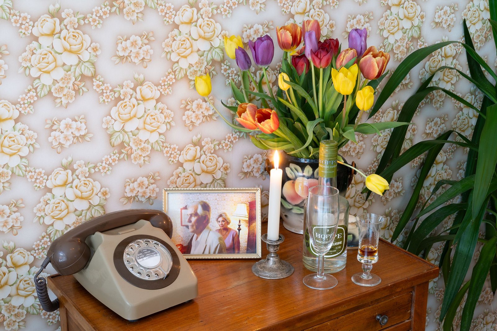 drawers with a rotary phone, picture in frame, lit candle and flowers